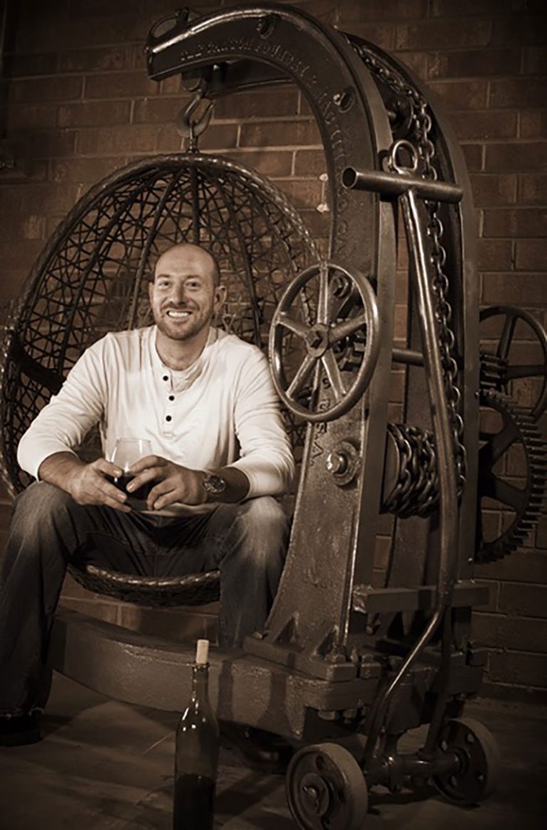 Chris-Lutzweiler-industrial-furniture-maker-sitting-in-his-rustic